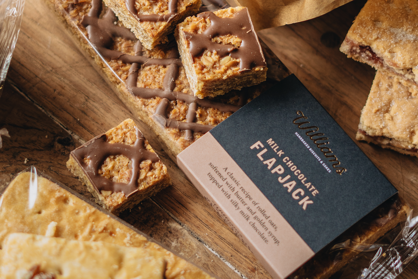 A close up shot of a pack of milk chocolate flapjack with cut up pieces of flapjack sat on top of the packaging. 